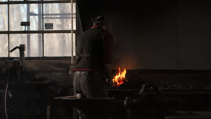 The man in black is standing at the fire and he is stroking it