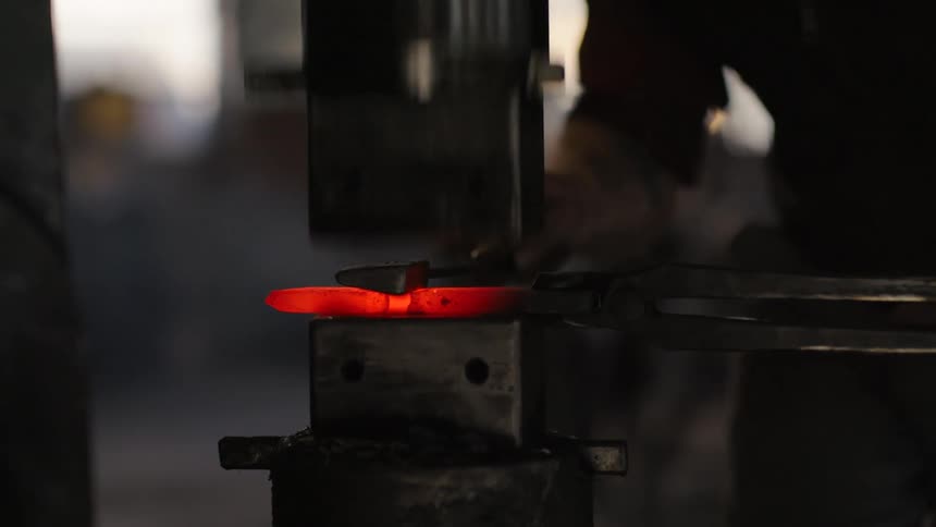 Heated metal part is pressed by a press while being manipulated with tongs in a forging environment