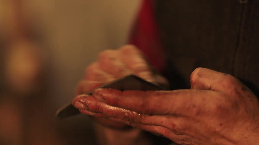 The man is rubbing something together in his hands that is oily