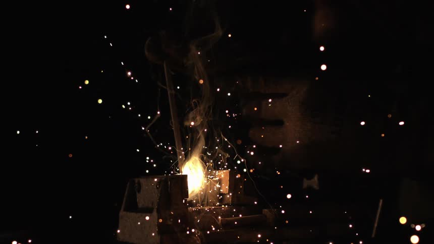 Bright sparks and smoke erupt from a welding process in a dimly lit environment