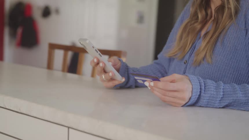 A woman is putting her credit card number into her cellphone