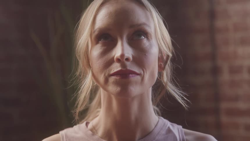 A woman looks up and down as she meditates