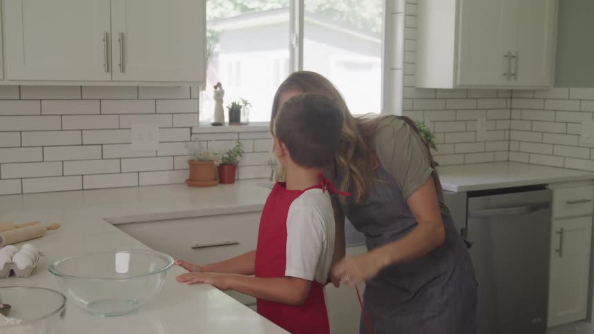 A mother is tying her sons apron as they get readh to cook