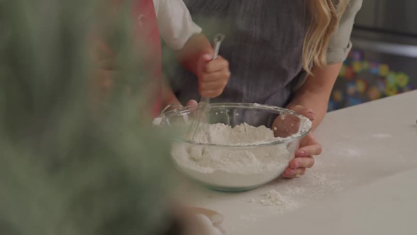 A mother is holding the bowl while her son stirs