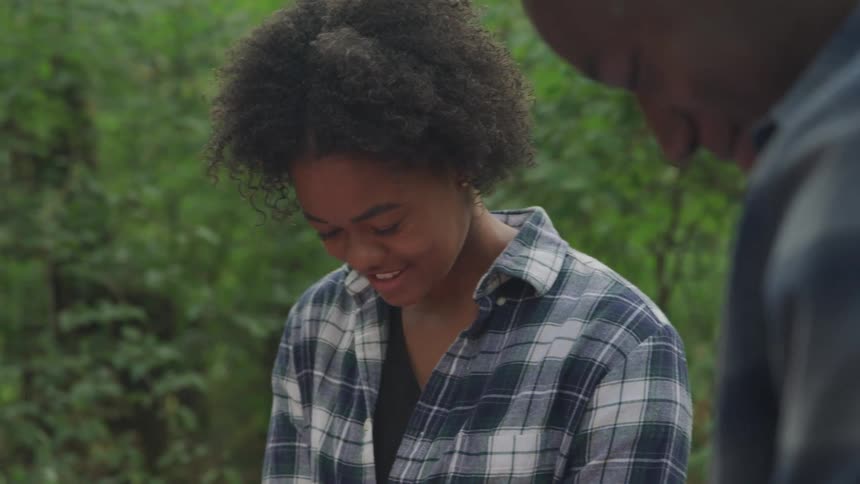Man and woman smiling while standing outdoors in a forest