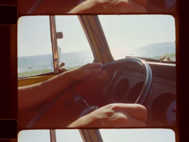 Man grips a large steering wheel as he drives an old truck