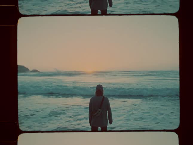 A man stands on the beach as the sun rises