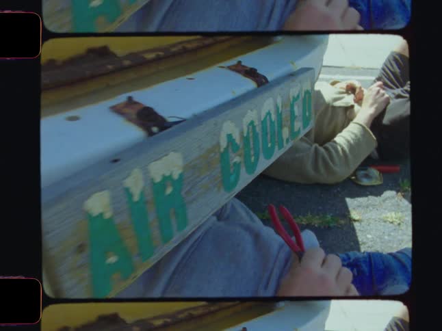 Two men are using tools to fix a vehicle from underneath
