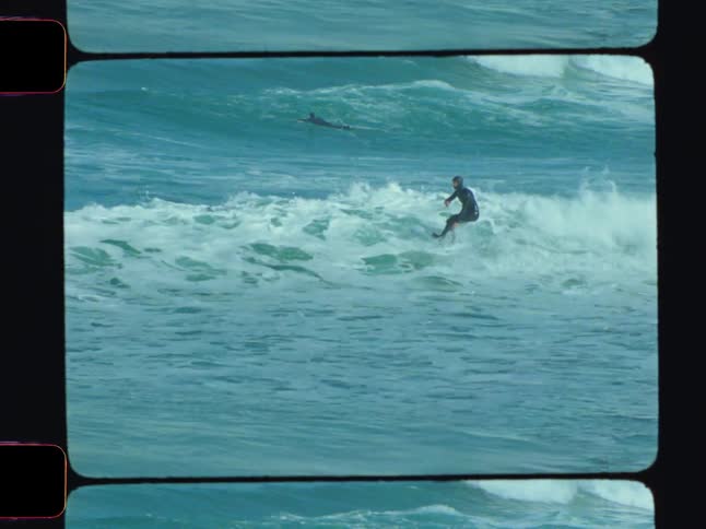 A man in a wetsuit surfs an ocean wave with a surfboard on a clear day