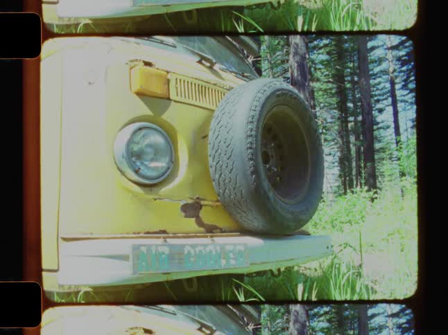 A camper parked in the grass has a sprea tire attached to the front