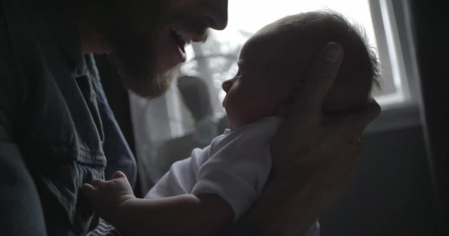 Father holds his baby and kisses his forehead