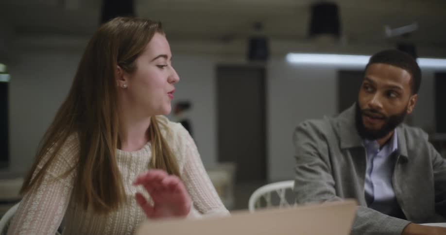 Man and woman sitting at a table hold a discussion in an office building