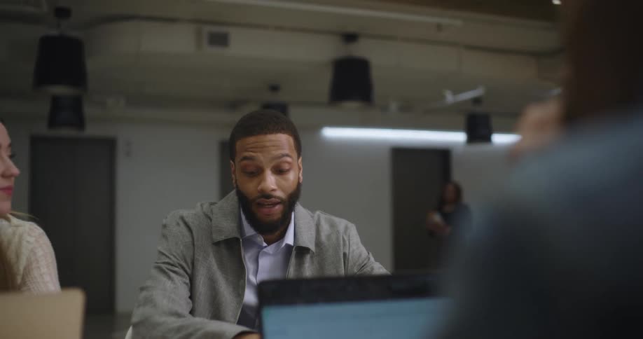 A man talks with two workers in the office