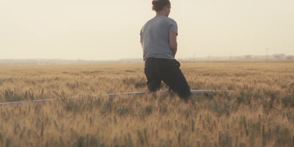Man maneuvers an irrigation pipe in a field on a foggy day