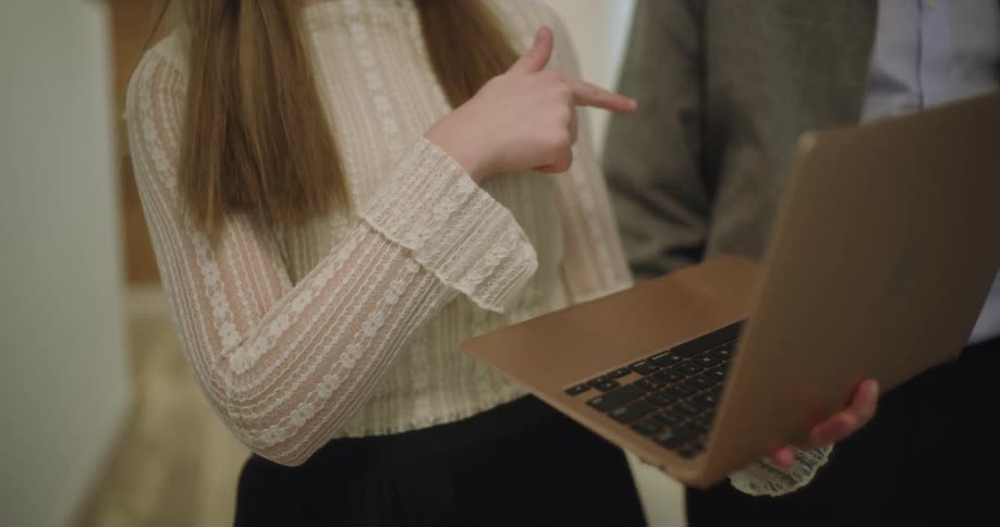 A woman talks with a man while carrying a laptop