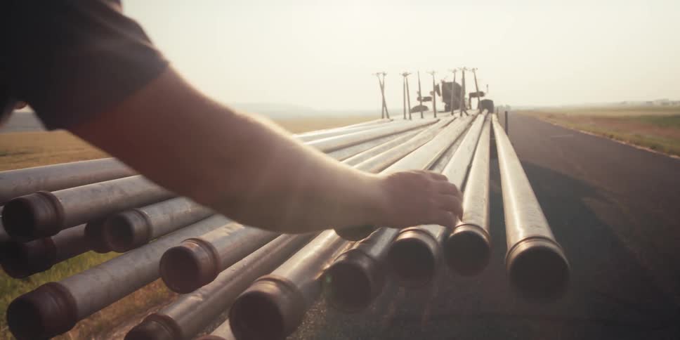 A tractor driver is counting the pipes from his trailer