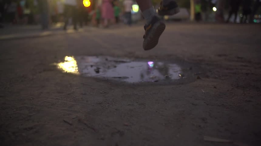 Child running and stomping in a puddle
