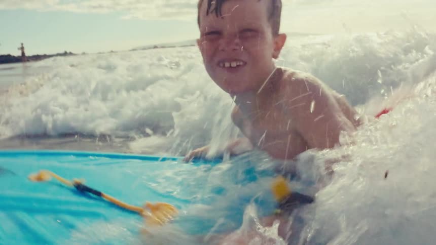 A child is playfully immersed in frothy ocean waves