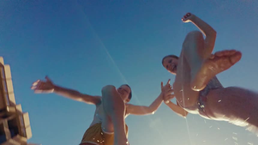The brother and sister jump into the pool while holding hands