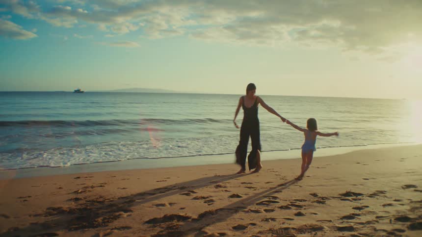 A woman and her daughter dance on the beach