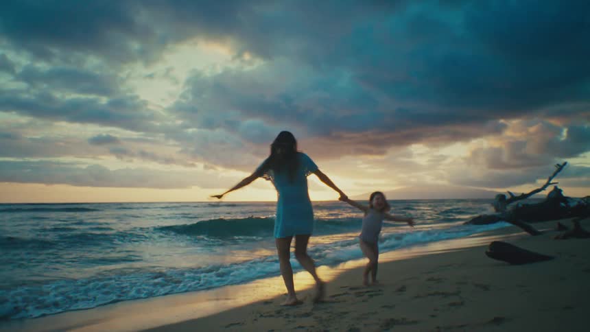 Mom and daughter playing happily on the shore of a beach