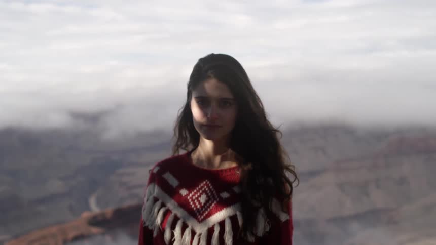 A woman stares from atop a cliff