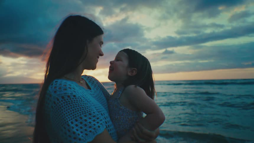 A woman holds her daughter and gives her a kiss