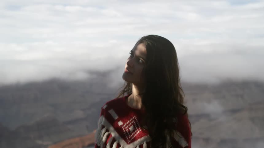 A woman closes her eyes briefly on a mountain