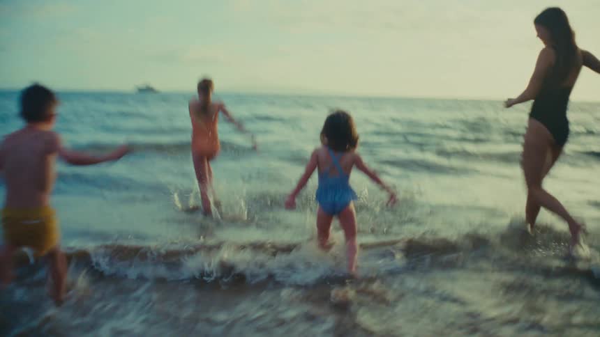 A mother and her children run into the water at a beach