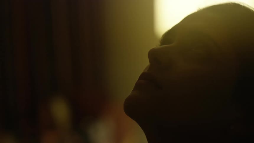 Silhouette of a woman in a room staring forward and then looking up towards the ceiling