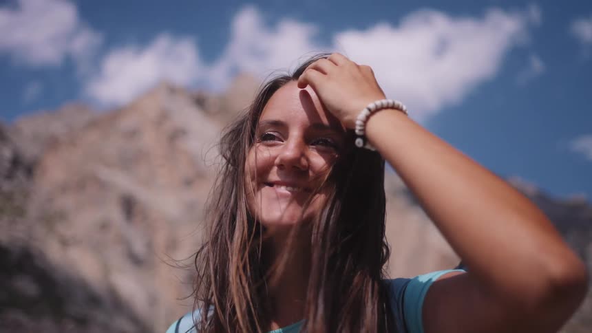 A woman hiker pulls her hair back and smiles