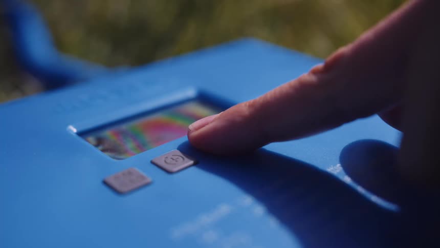 Person pushes a button to set a device to auto on a summer day