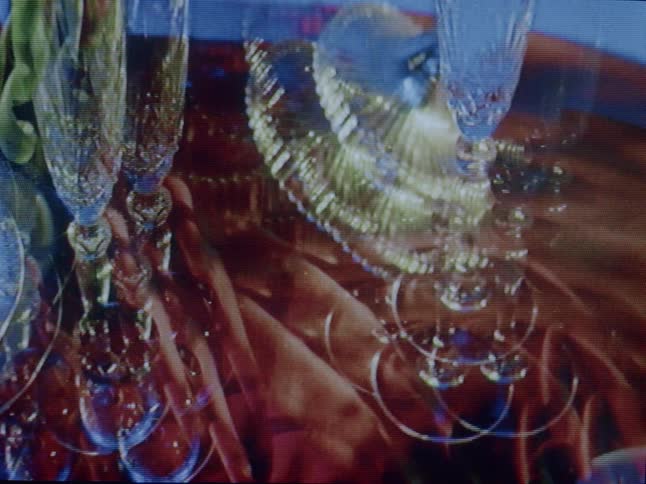 A closeup presents an abstract composition of glassware with a double exposure effect highlighted by projected light
