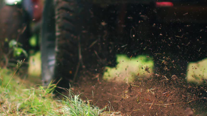Passing vehicle throws dirt and grass into the air from dirty tires