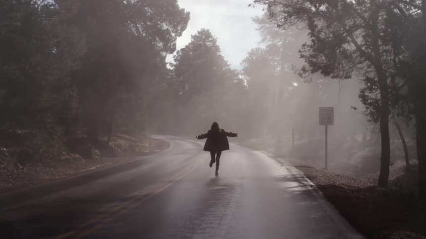 A person is running down a foggy street