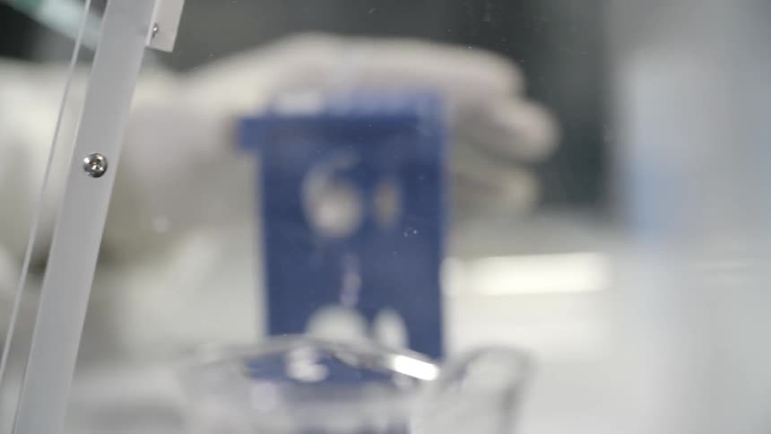 A laboratory worker extracts liquid from a canister