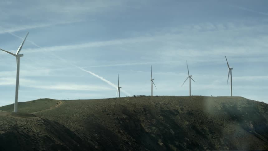 Windmills spin atop a cliffside