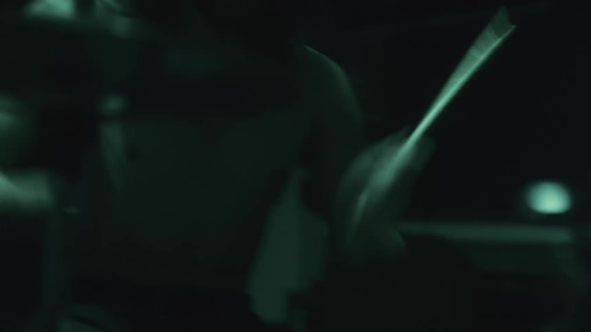 A man is playing the drums shirtless