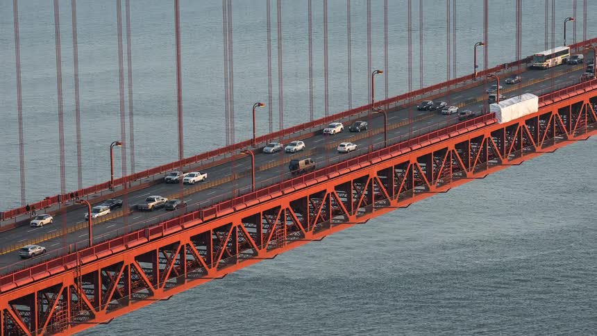An aerial spedup view tracking a car traveling along the golden gate bridge