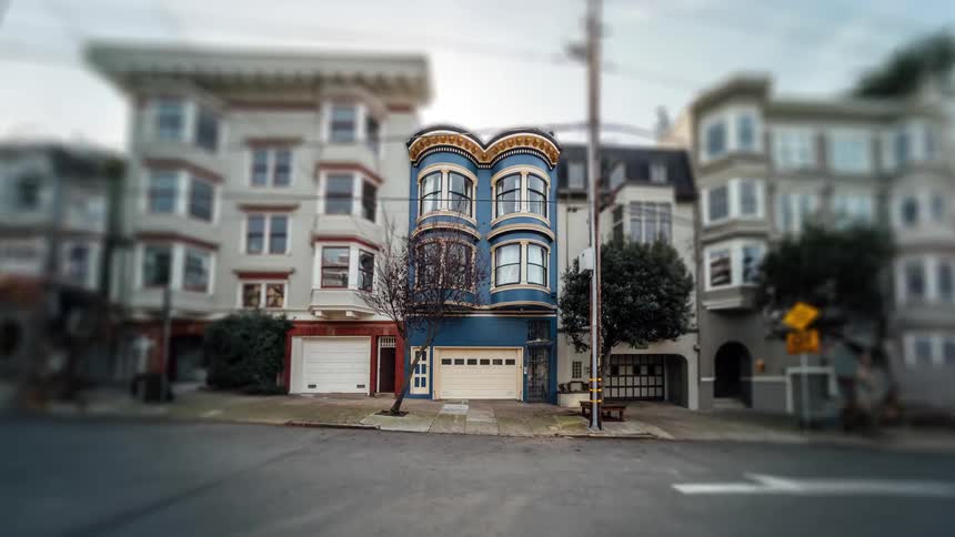 A row of colorful victorian houses lining a steep san francisco street with cars parked along the curb