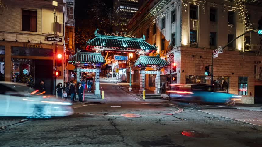A nighttime view of chinatowns iconic gate with blurred cars passing by