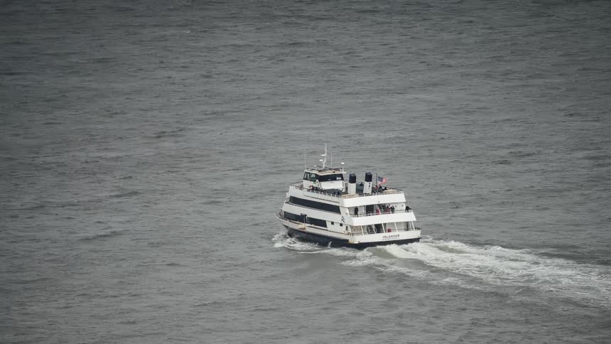 A timelapse tracks a ferry boat as it speeds across the water with people visible on board