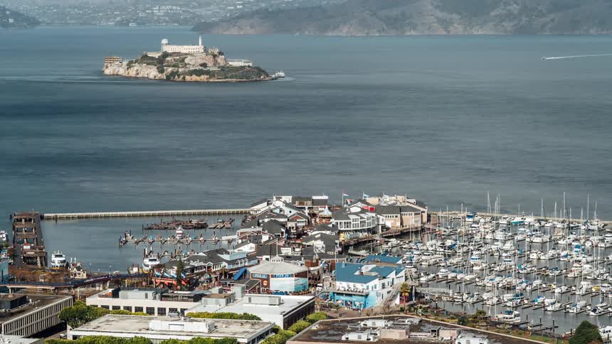 A lot of boats are in a marina at the waterfront of a city with an island off the coast