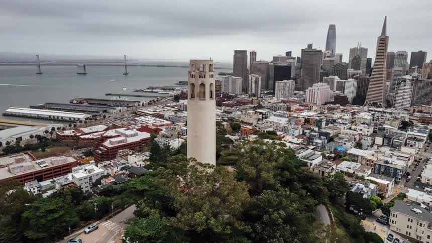 View of a large city with many buildings and a tower and sea on the horizon