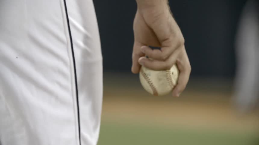A man holding a baseball and the camera is zoomed in on him