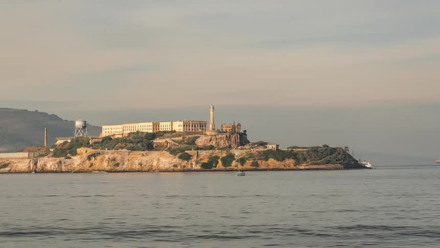 A boat passes by a prison sitting on an island
