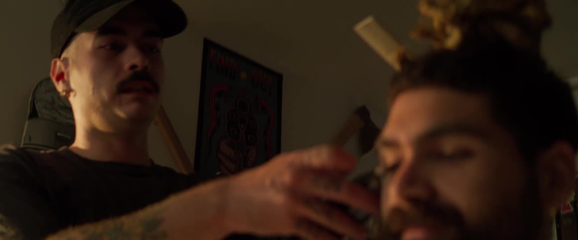 A man is getting a haircut while the barber talks with him