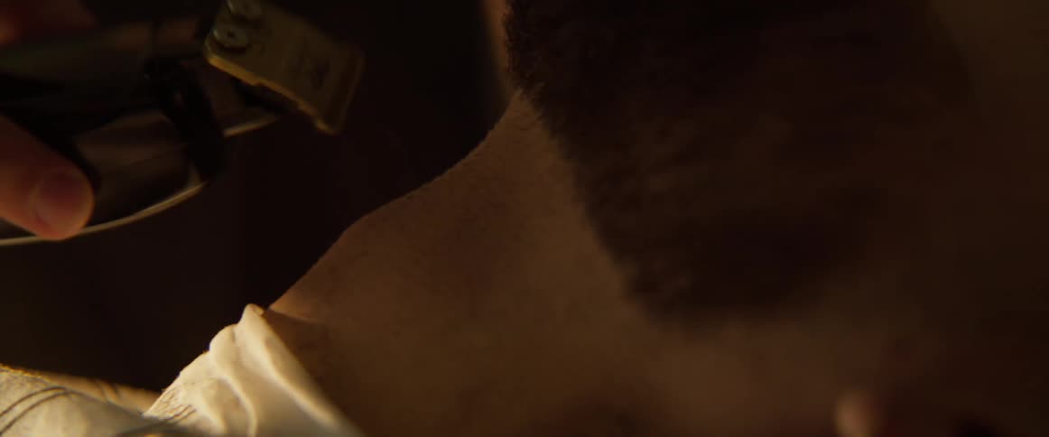 A barber is trimming a mans beard by the neck