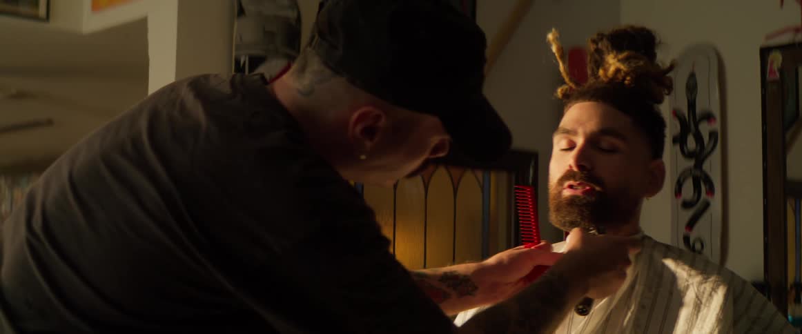 Barber trims a mans beard with clippers