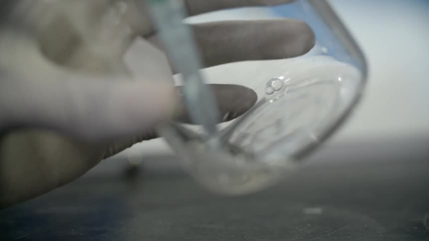 A needle is removing water from a beaker